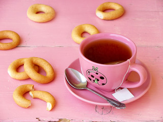 cup of tea, bagels and cookies on a pink background