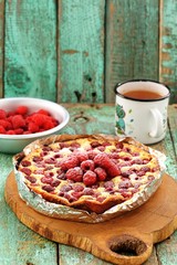 Homemade quark pie with raspberries in foil served on wooden board