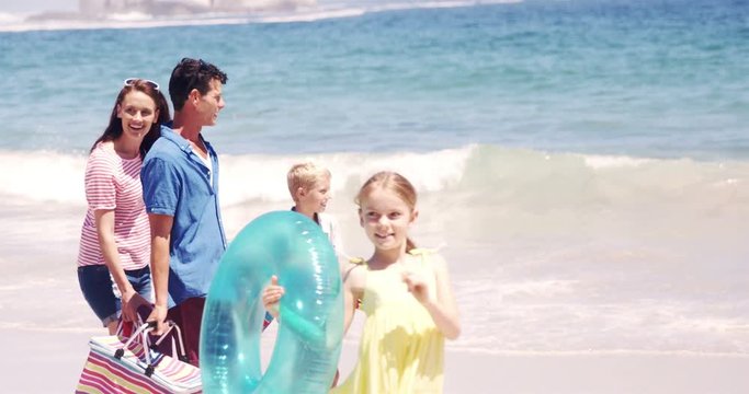 Young family walking together with picnic stuff on the beach