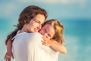 Portrait of happy mother and little daughter on sunny beach