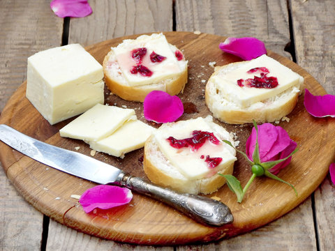 sandwiches with cream cheese and jam of tea roses on a wooden board