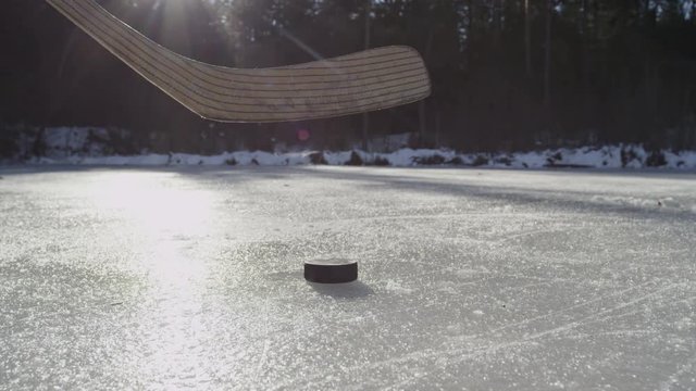SLOW MOTION CLOSE-UP: Hockey player hitting puck on frozen lake