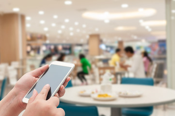 Hand with smartphone on foot court