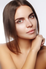 Beautiful young woman with clean face, shiny skin, fashion natural make-up, perfection eyebrows. Cute bun hairstyle. Spa portrait, naturel cosmetics, healthy fresh look