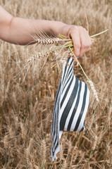 Fototapeta na wymiar détail main de femme et chapeau dans un Champ de blé