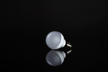 Energy saving lamp on black background. Sales of light bulbs. Advertising for energy-saving bulbs. Place for your text.
