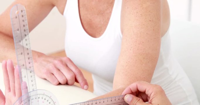Physiotherapist examining patients wrist with goniometer