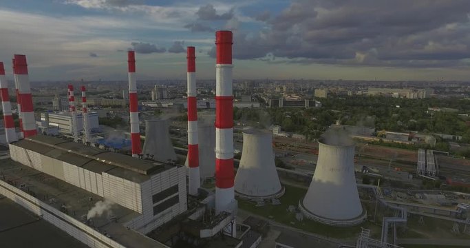 Aerial 4K: Pollution concept, Smoke or Steam from an Industrial Chimney, Thermal Power Plant with Huge Cooling Towers and Steam situated in the Ciity, Industry Scenery, Factory View. 