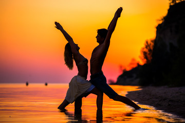 Fototapeta premium An attractive young woman and man doing yoga on the beach, Sea