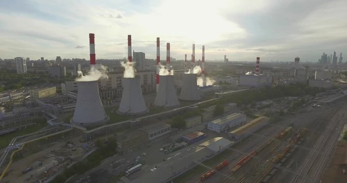 Aerial 4K: Pollution concept, Smoke or Steam from an Industrial Chimney, Thermal Power Plant with Huge Cooling Towers and Steam situated in the Ciity, Industry Scenery, Factory View. 
