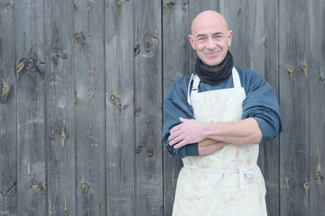 Smiling Man with Arms Crossed by a Wooden Background