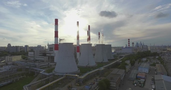 Aerial 4K: Pollution concept, Smoke or Steam from an Industrial Chimney, Thermal Power Plant with Huge Cooling Towers and Steam situated in the Ciity, Industry Scenery, Factory View. 