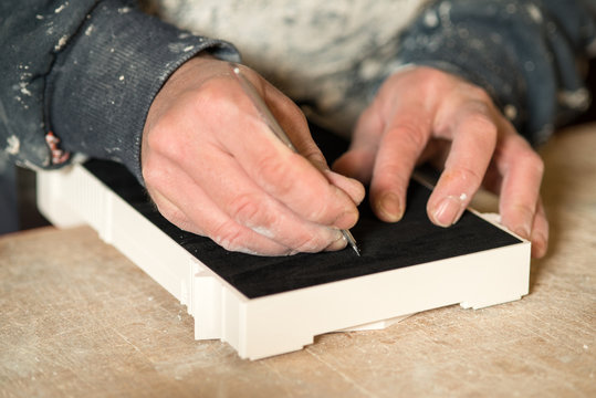 Hands Cutting Black Felt Paper on a Plaster Model