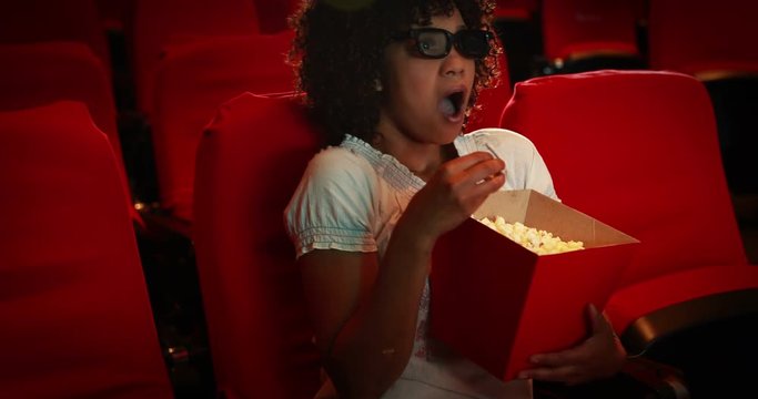 Young woman watching scary movie at the cinema 
