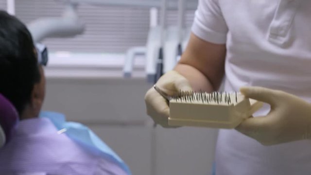 The dentist holding medical tweezers is choosing appropriate drill for dental instrument