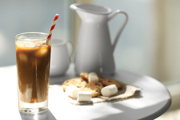 Iced coffee with straw on white table in cafe