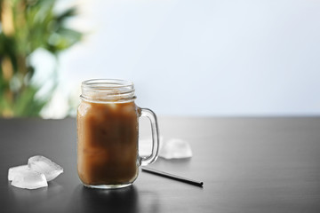 Iced coffee and straw in glass jar on black table