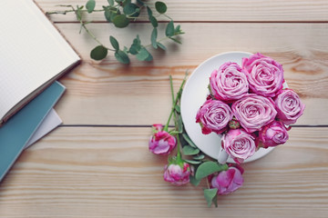 Fresh roses bouquet in cup on wooden table