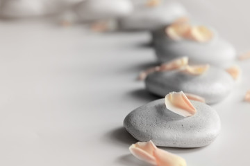 Spa stones with petals on light background