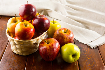 Apples in the small wicker basket on dark wooden background