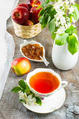 Cup of tea and apple jam on rustic wooden table