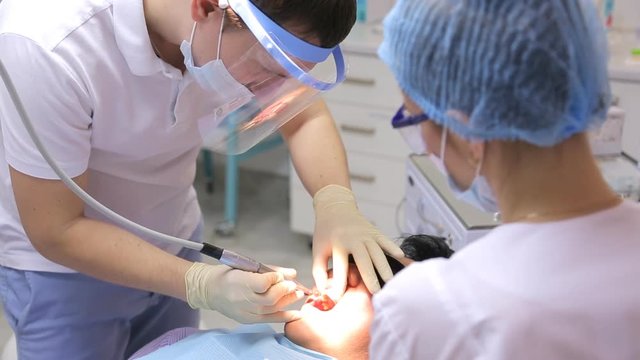 Dentist is doing teeth whitening or other ordinary operation in mouth using dental equipment or instruments