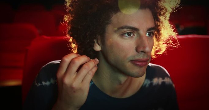 Young man watching a movie at the cinema 