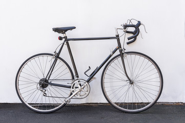 A vintage French road bike leaning against white wall background