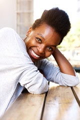 Fototapeta premium Beautiful african woman sitting at table and smiling