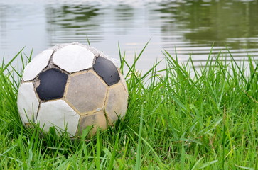 Old football on green grass in evening day,sport equipment.