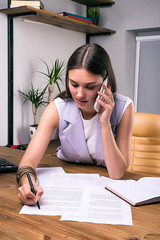Busy businesswoman using cell and writing notes