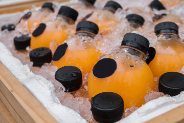 Obraz na płótnie Canvas Orange juice bottle cooling in ice cubes for sale.