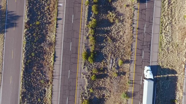 Aerial shot of a semi truck and cars on an interstate highway in the desert