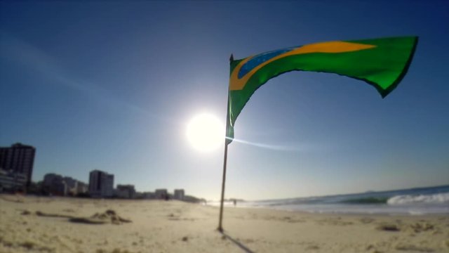 Brazilian flag blowing in the wind in morning sun on Ipanema Beach in Rio de Janeiro, Brazil