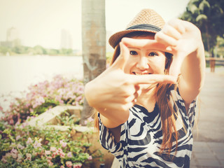 Beautiful Asian girl using hands framing for taking photos in outdoor scene - vintage tone