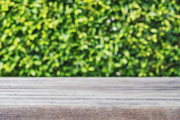 Wooden desk with defocus green bush with bokeh, vintage tone, selective focus, shallow depth of field