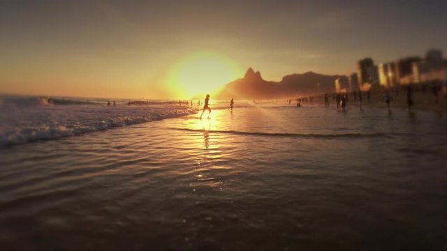 Sunset waves break on the shore of the Posto Nove section of Ipanema Beach, where locals gather to surf and play altinho beach football