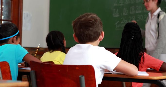 Pupils listening to their teacher at chalkboard in elementary school