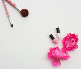 Obraz na płótnie Canvas Feminine flat lay blog photo background featuring makeup brushes, nail polish and a flower in a pink tone