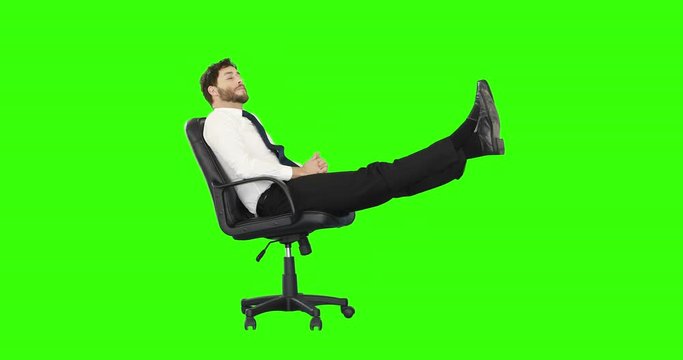 Businessman relaxing in his chair with legs up on green screen