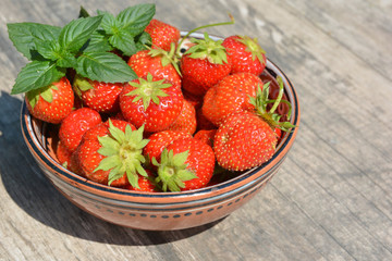 Clay Cup of red strawberries and sprigs of green mint