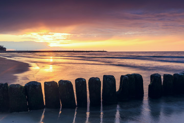 sunset on the beach with a wooden breakwater, long exposure