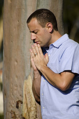 Praying by a tree outdoors.