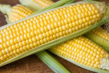 Ripe yellow corn cob on brown wooden board
