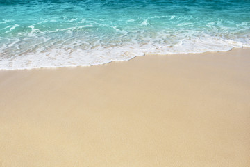 Fototapeta na wymiar Soft wave of blue ocean on the sandy beach, background.