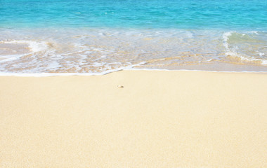 Fototapeta na wymiar Soft wave of blue ocean on the sandy beach, background.