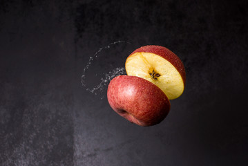 half red apple splashes in air
