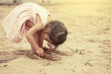 Child asian cute little girl playing with sand in playground