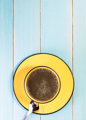Yellow cup of coffee on retro table top view