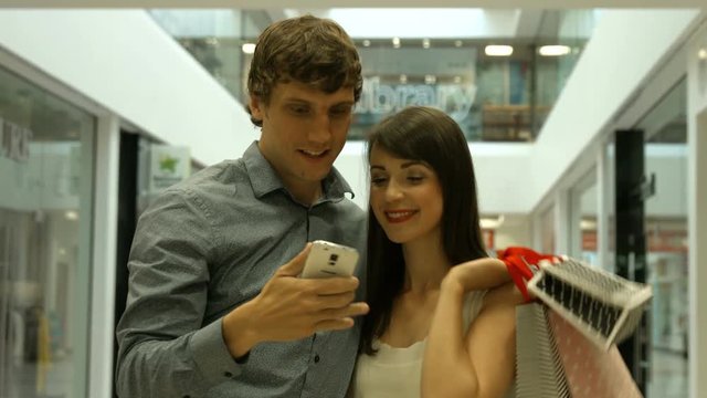 Smiling couple taking selfie in shopping mall 